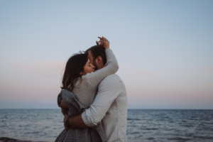 Un homme et une femme cultivent la tendresse dans leur couple en s'enlaçant sur la plage
